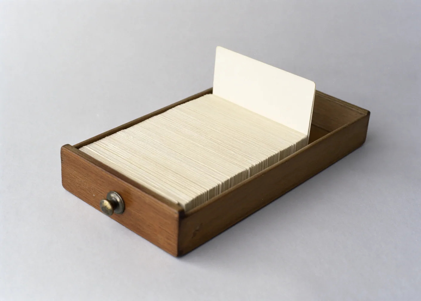 An open card index drawer packed with cards on end, one card raised above the rest.